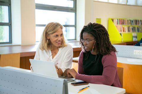 Student and teacher working on laptop