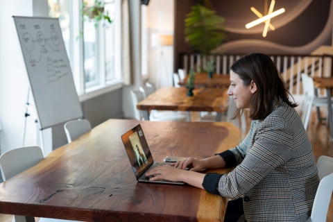 Woman looking at a coworker on her laptop screen