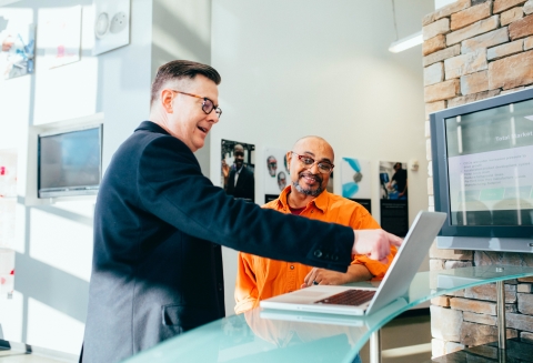 Person pointing at a laptop and smiling with coworker