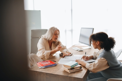 teacher and student talking and writing on paper