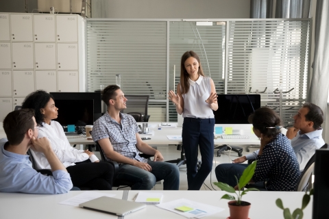 Woman standing and talking to seated colleagues