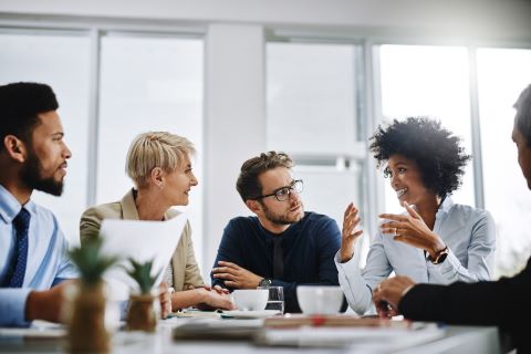 Colleagues sitting around a conference table talking