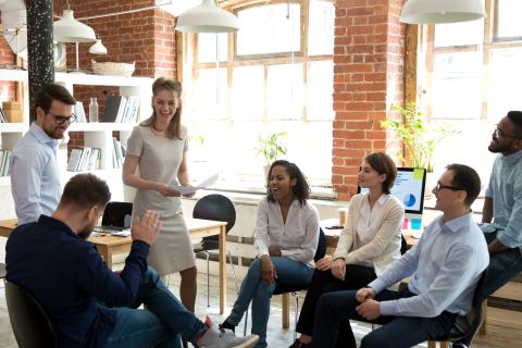 Team of workers sitting in a circle talking and smiling